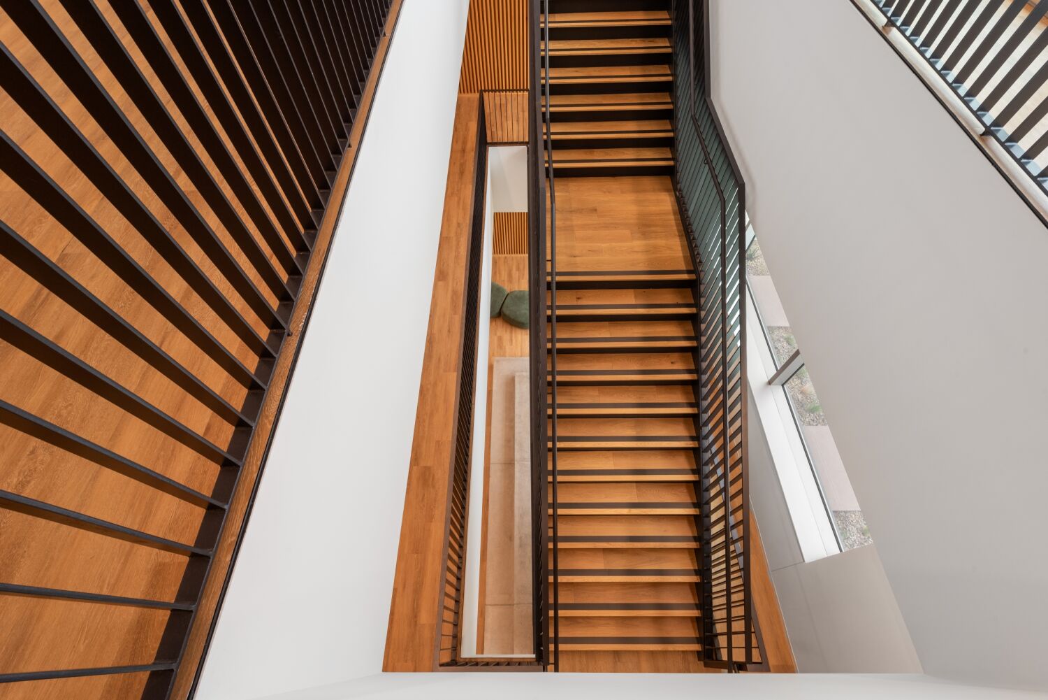 Overhead view of a Medtronic office stairwell featuring black metal railings, wood treads, white walls, and adjacent windows allowing natural light into the space.