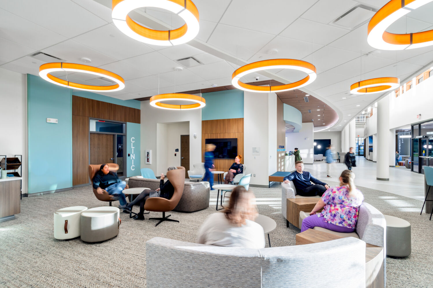Waiting area at the Casper–Natrona County Health Department with circular lounge seating, upholstered chairs, low tables, and ring pendant lighting.