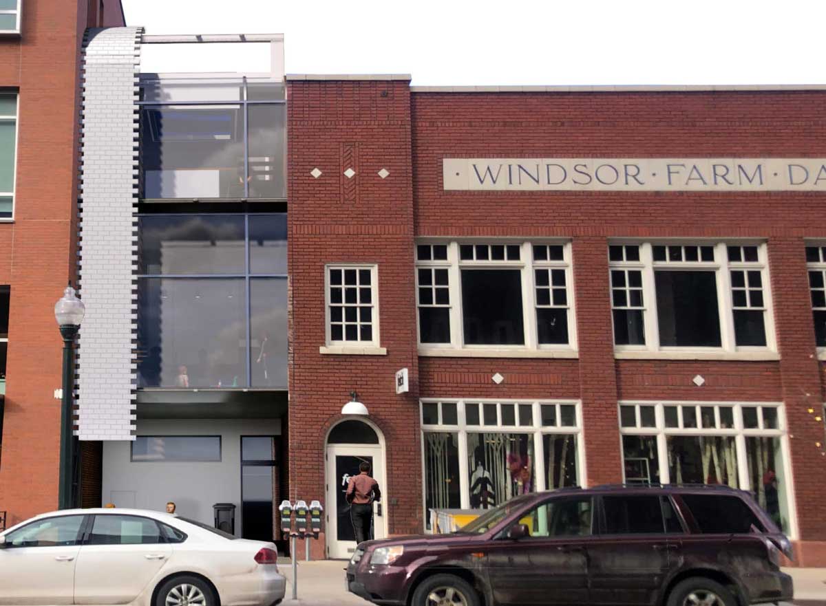 A three story red brick building with shops, parking, and residential living integrated. 